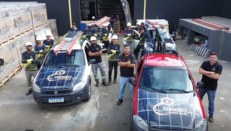 Equipe da Target uniformizada ao lado dos carros adesivados da frota