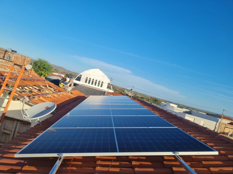 Fileira de placas solares em diagonal contra o céu azul do sertão
